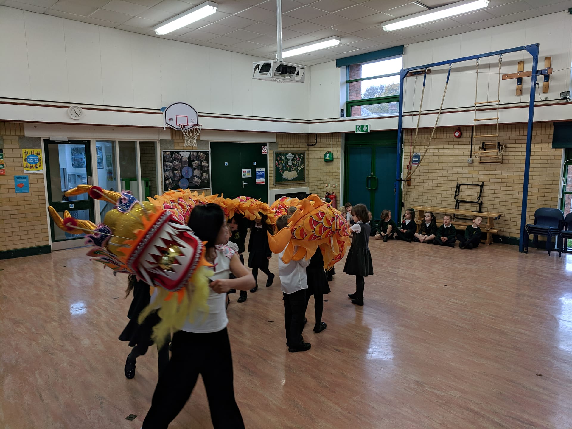 School children dancing in hall with chinese dragon