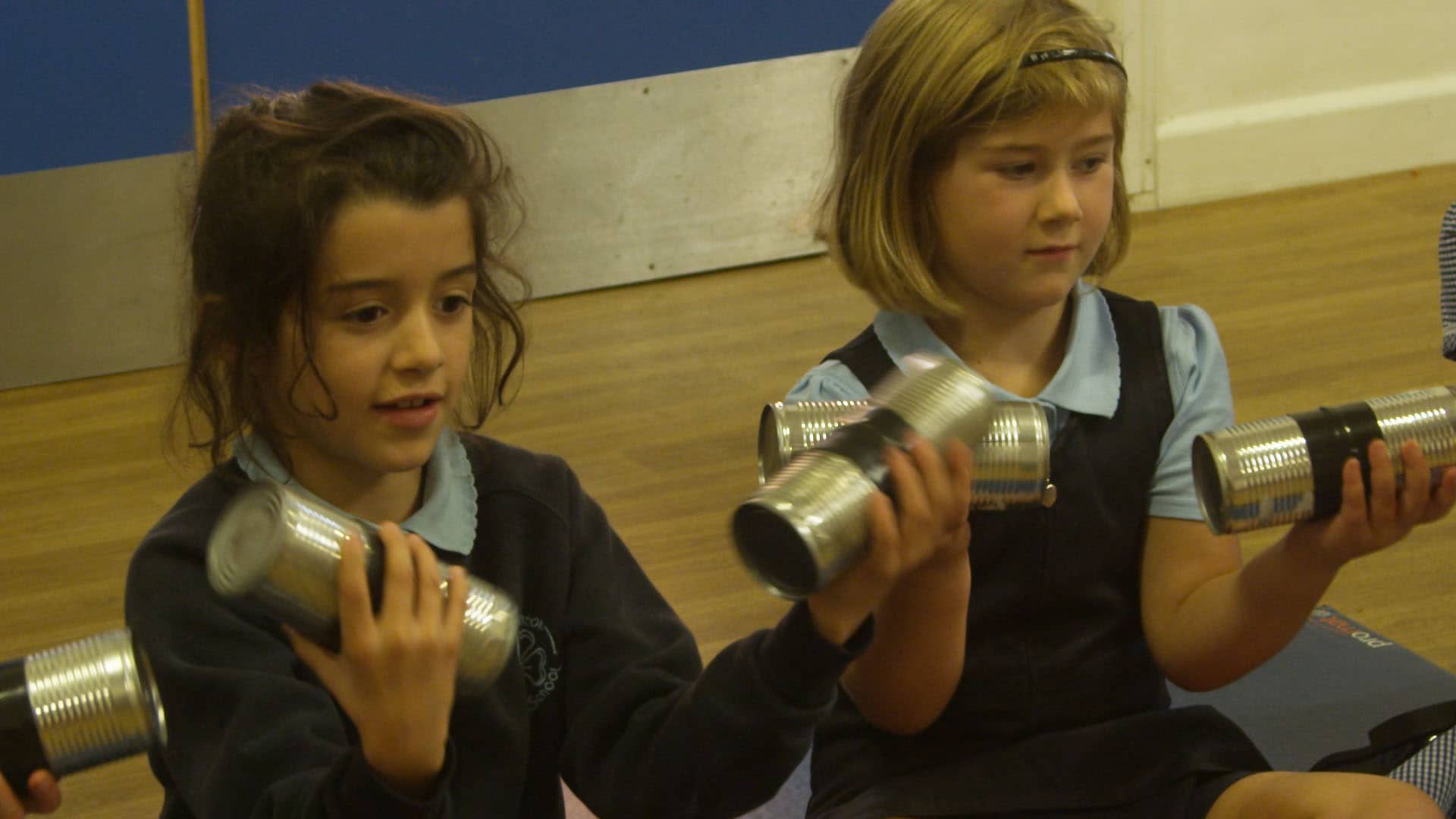 School children playing music on recycled tin cans