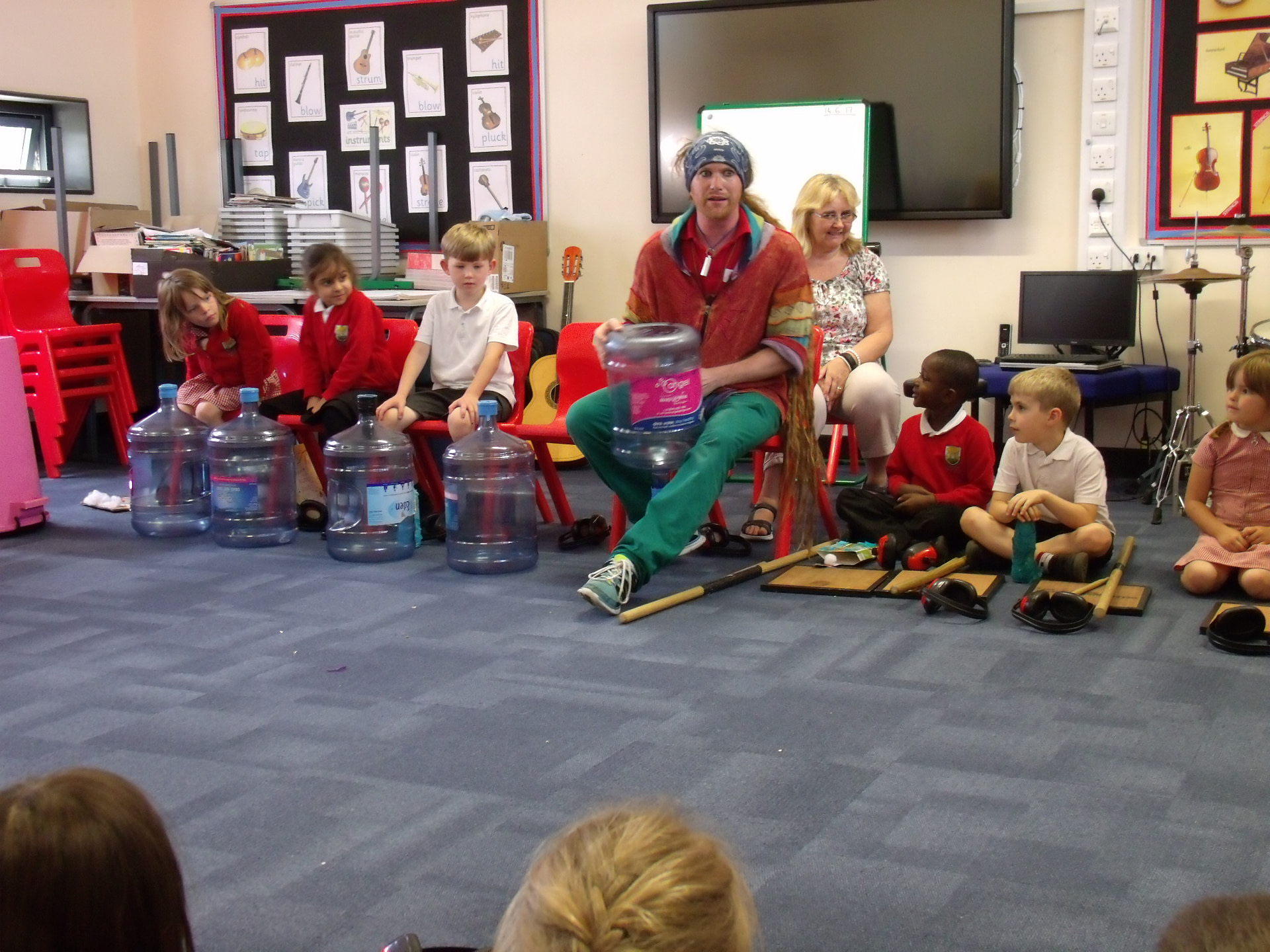 Teacher demonstrating how to play musical instruments made out of bottles