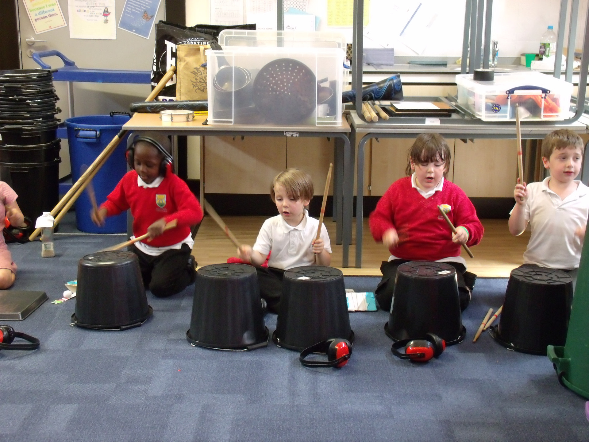 School children playing music on large empty buckets