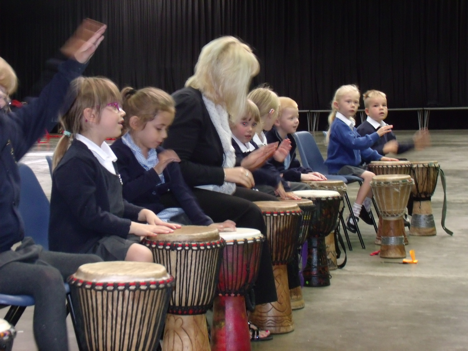 Children sat in line at school learning African drumming