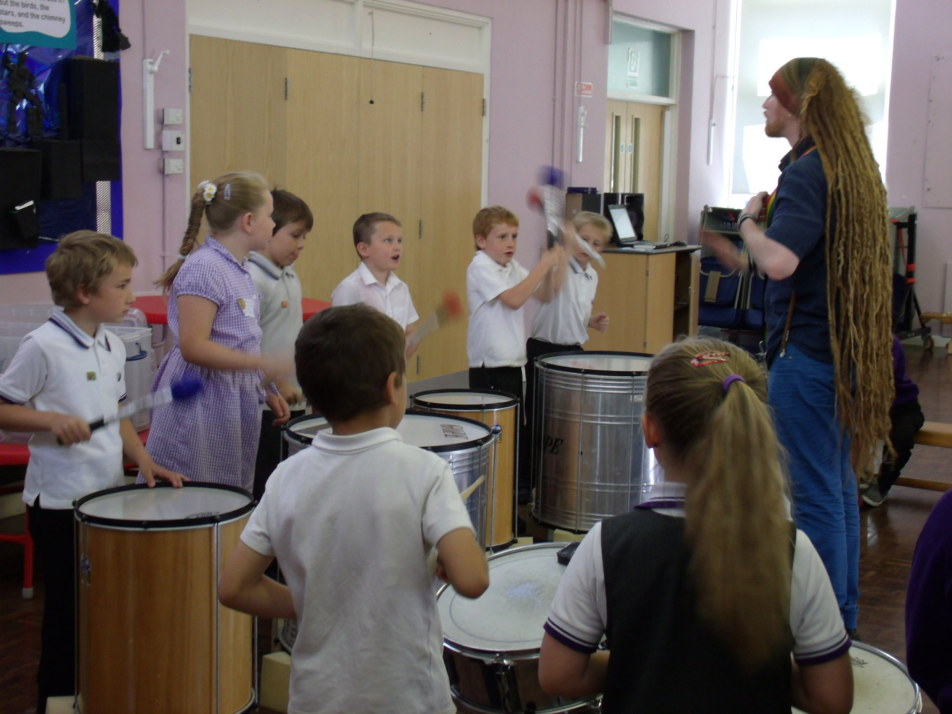 Teacher demonstrating to school children how to play Samba drums