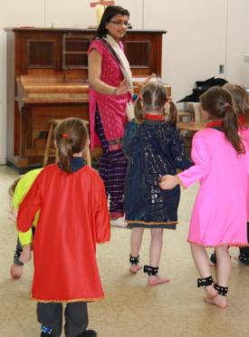 Children being taught by teacher Indian dancing wearing Indian dresses